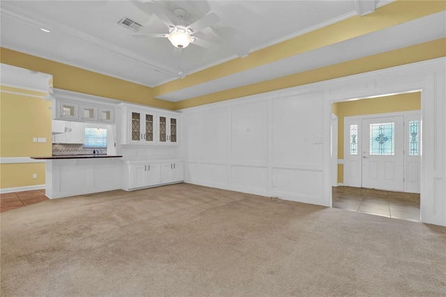 unfurnished living room featuring light colored carpet, a decorative wall, visible vents, and light tile patterned floors