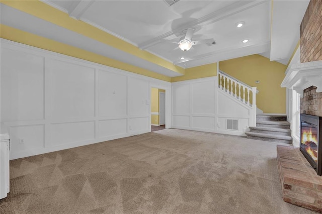 unfurnished living room with carpet, a fireplace, visible vents, a decorative wall, and stairs