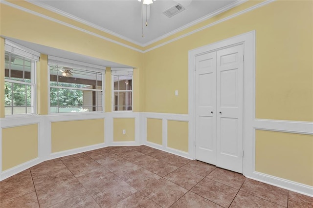 unfurnished room featuring ceiling fan, tile patterned flooring, a decorative wall, visible vents, and ornamental molding