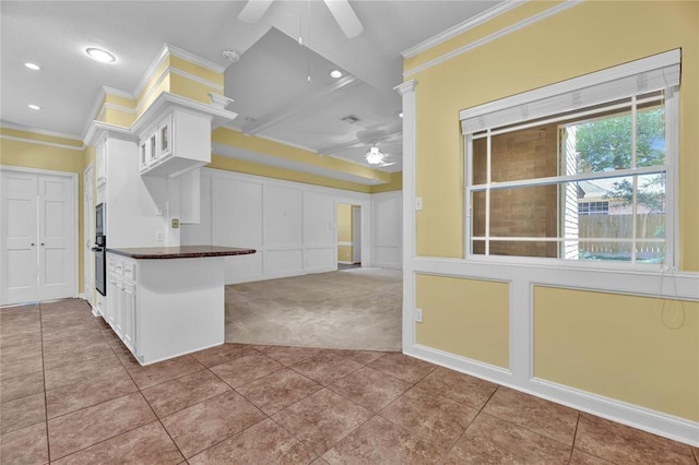 kitchen with carpet floors, ornamental molding, a ceiling fan, and white cabinetry