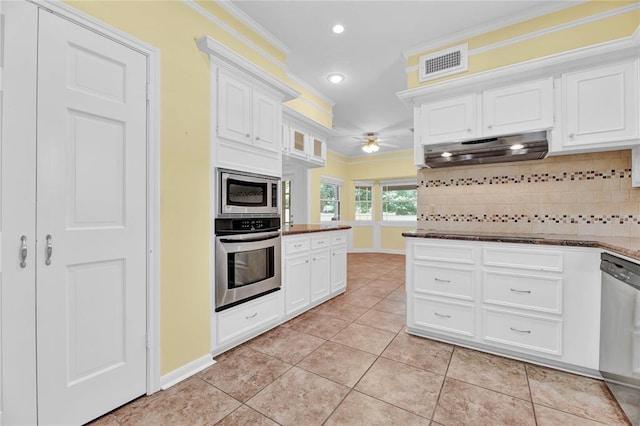 kitchen with under cabinet range hood, stainless steel appliances, visible vents, ornamental molding, and decorative backsplash