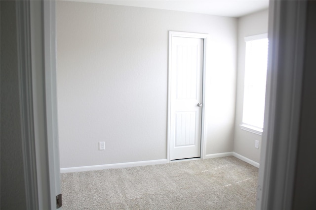 spare room featuring a wealth of natural light and light colored carpet