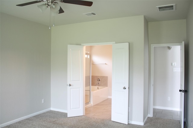 unfurnished bedroom featuring ensuite bathroom, light colored carpet, and ceiling fan