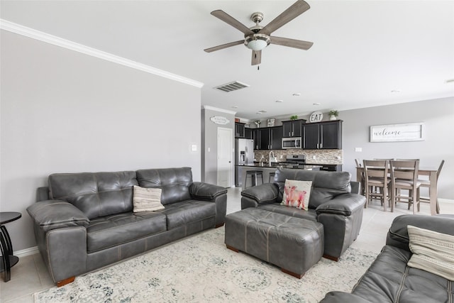 living room featuring light tile patterned floors, crown molding, sink, and ceiling fan