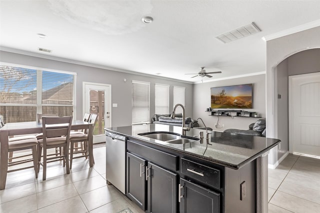 kitchen featuring sink, dark stone countertops, stainless steel dishwasher, crown molding, and a center island with sink