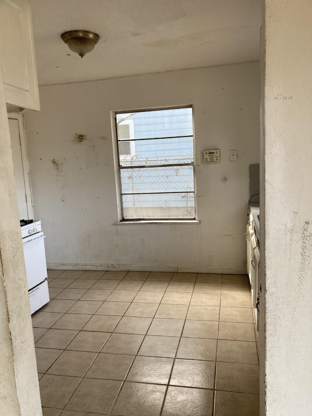 interior space featuring light tile patterned flooring, white range with gas stovetop, and white cabinets