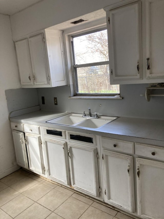 kitchen featuring white cabinetry, sink, and light tile patterned flooring