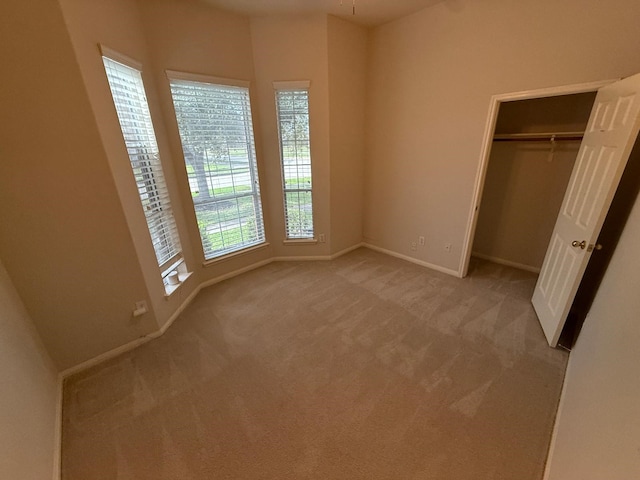 unfurnished bedroom with light colored carpet and a closet