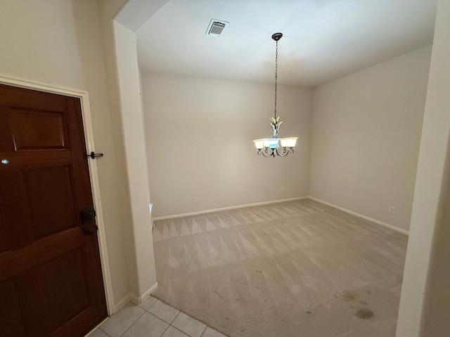 carpeted empty room featuring a notable chandelier