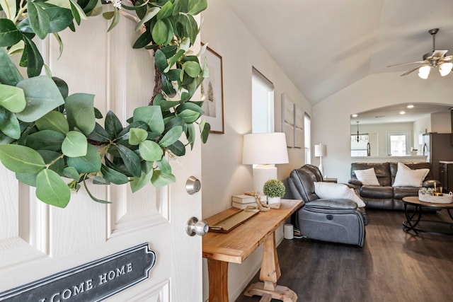 living room featuring a ceiling fan, arched walkways, vaulted ceiling, and wood finished floors