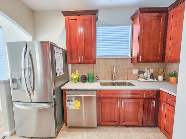 kitchen with appliances with stainless steel finishes, sink, light tile patterned floors, and decorative backsplash