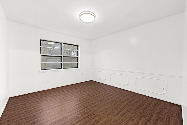 unfurnished room with a wainscoted wall and dark wood-type flooring