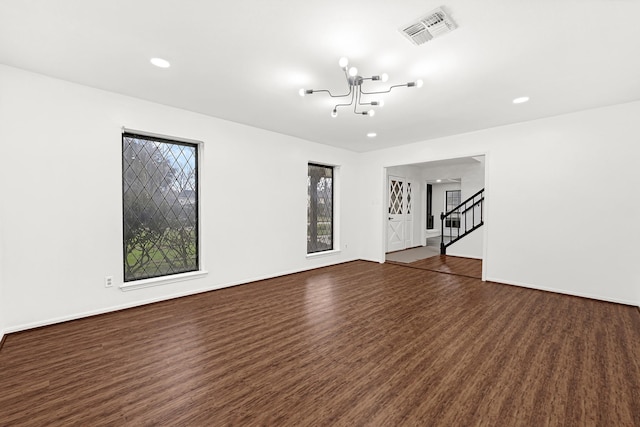 empty room featuring dark wood finished floors, visible vents, stairway, a chandelier, and baseboards