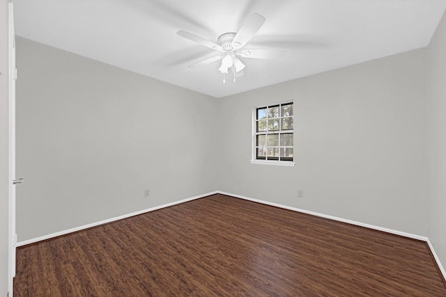 empty room with dark wood finished floors, a ceiling fan, and baseboards