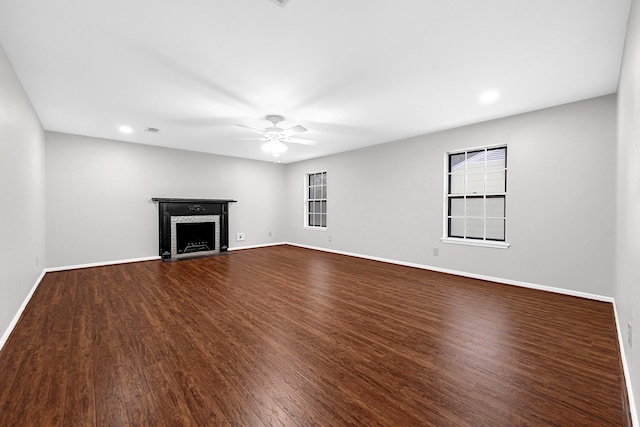 unfurnished living room with dark wood-style floors, ceiling fan, a fireplace, and baseboards