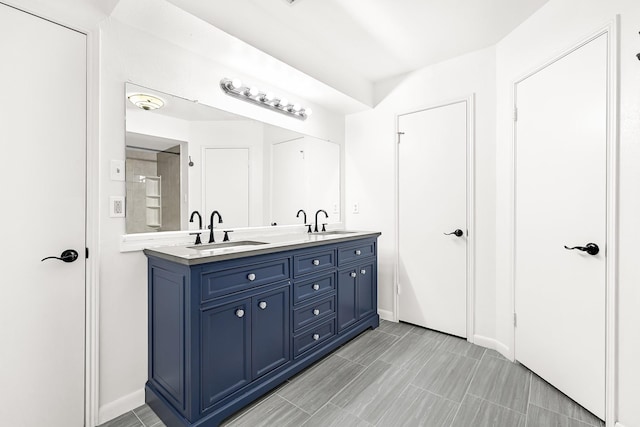 full bathroom with double vanity, a sink, and baseboards