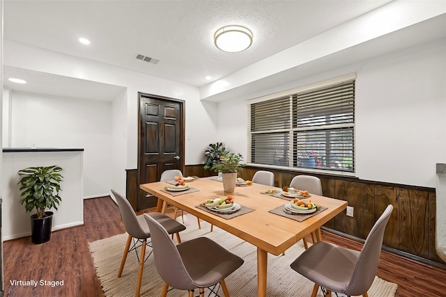 dining room with wooden walls, visible vents, wood finished floors, and wainscoting