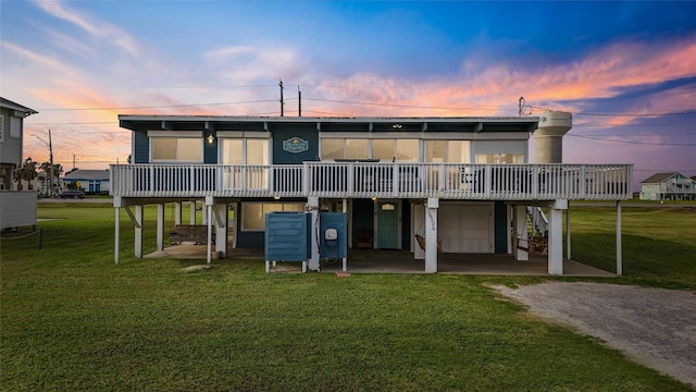 back house at dusk with a yard, a deck, and a garage