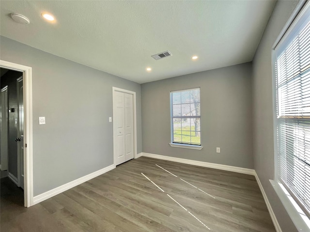 empty room with a textured ceiling and dark hardwood / wood-style flooring