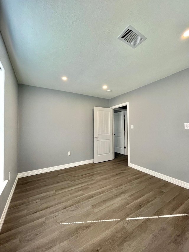 unfurnished room featuring dark wood-type flooring and a textured ceiling