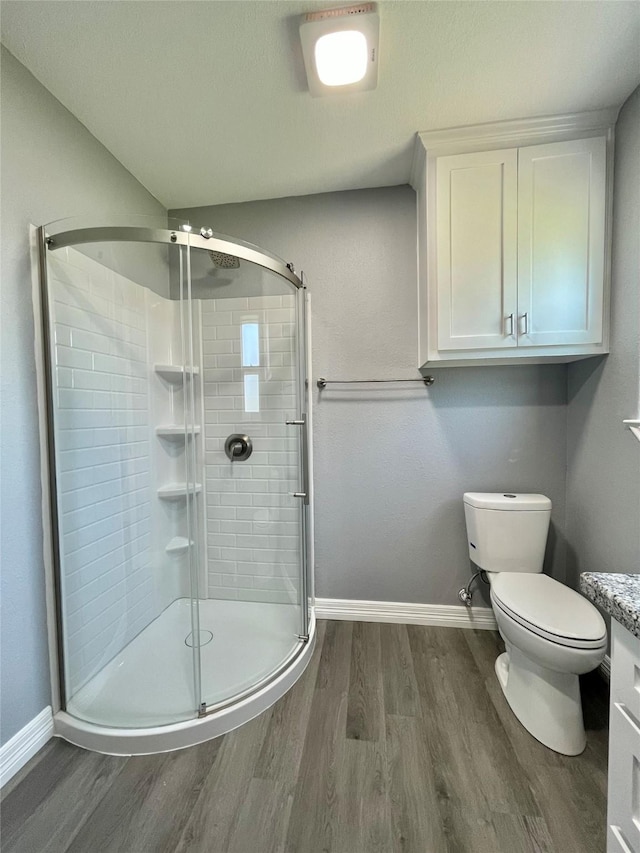 bathroom with hardwood / wood-style flooring, vanity, toilet, and walk in shower