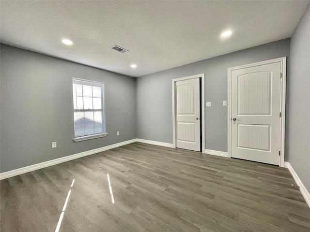 spare room featuring dark hardwood / wood-style floors and a textured ceiling