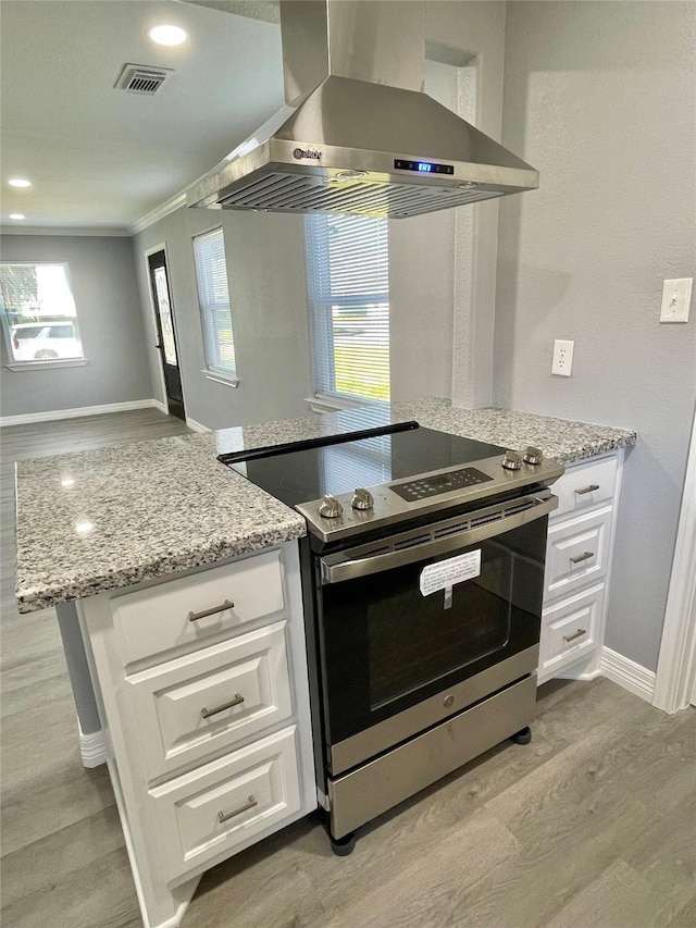 kitchen featuring light hardwood / wood-style flooring, light stone counters, extractor fan, white cabinets, and stainless steel range with electric cooktop