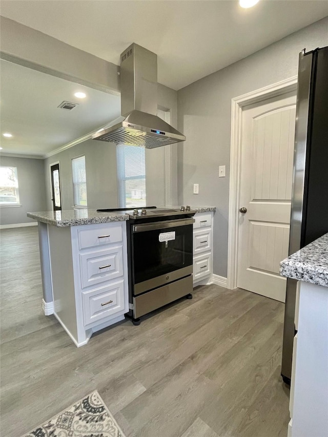 kitchen with white cabinets, appliances with stainless steel finishes, light stone countertops, and exhaust hood