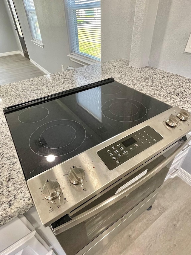 interior details featuring light stone countertops and electric stove