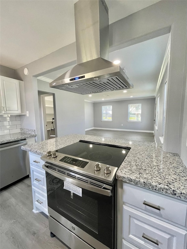 kitchen with tasteful backsplash, white cabinetry, island exhaust hood, stainless steel appliances, and light wood-type flooring