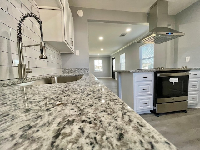 kitchen with sink, island range hood, white cabinets, and stainless steel electric range oven