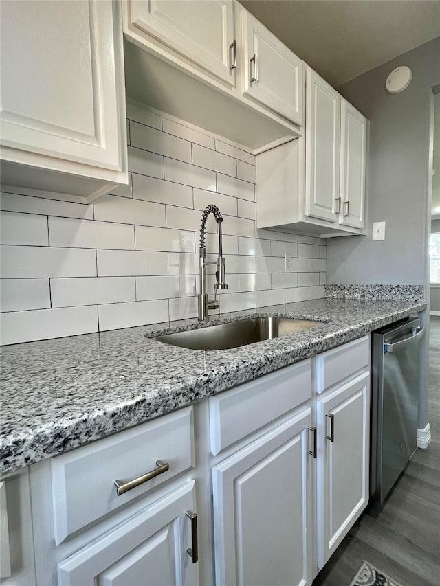 kitchen featuring sink, tasteful backsplash, light stone counters, stainless steel dishwasher, and white cabinets