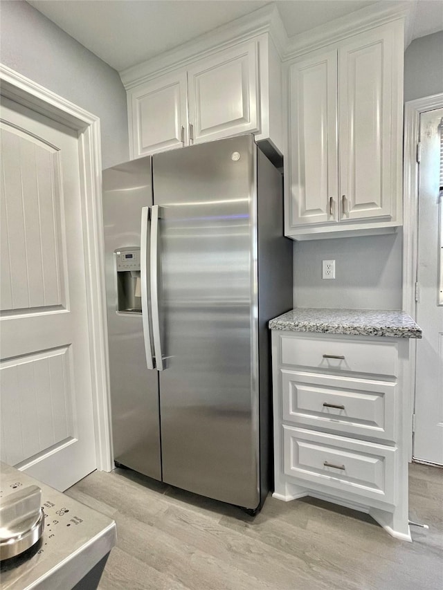 kitchen featuring white cabinetry, stainless steel fridge with ice dispenser, light stone counters, and light wood-type flooring