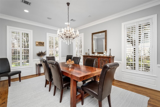 dining space featuring a wainscoted wall, crown molding, visible vents, and wood finished floors