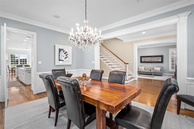 dining area with ornamental molding, light wood finished floors, stairway, and wainscoting