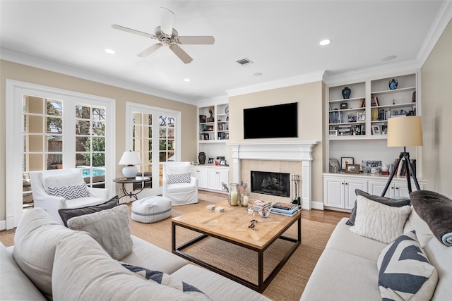 living area with light wood-style floors, visible vents, and crown molding