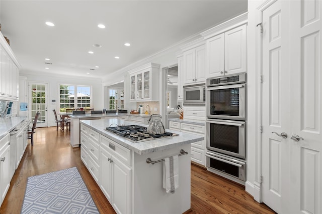 kitchen with a warming drawer, appliances with stainless steel finishes, white cabinets, and crown molding