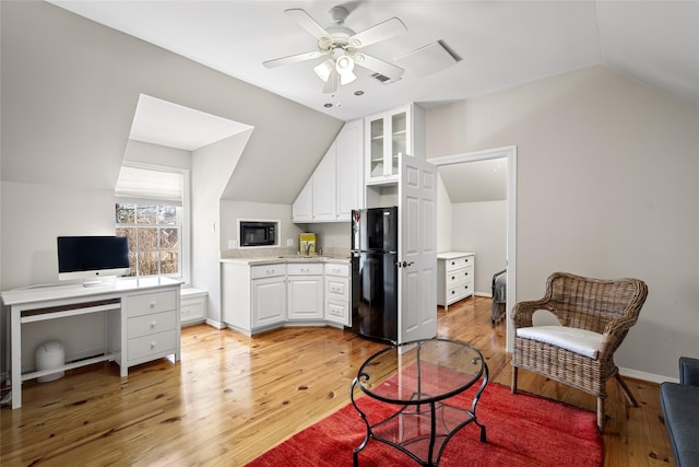 living area featuring lofted ceiling, visible vents, light wood-style floors, a ceiling fan, and baseboards