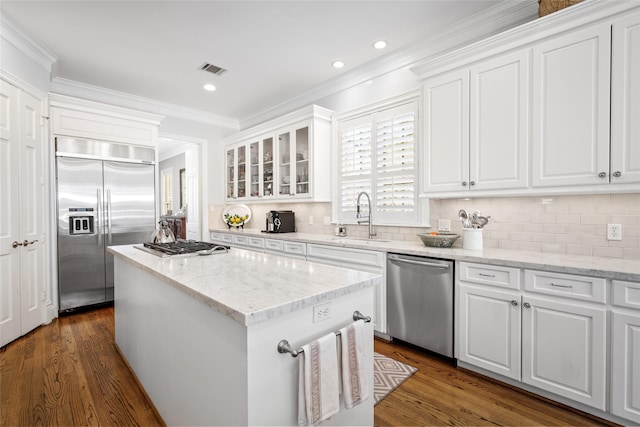 kitchen featuring a center island, stainless steel appliances, crown molding, white cabinetry, and a sink