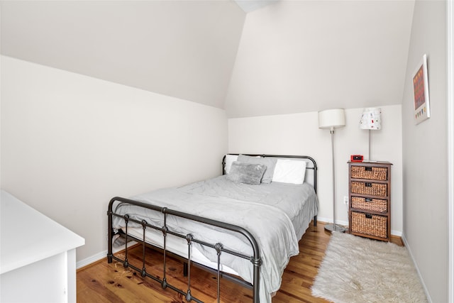 bedroom with lofted ceiling, wood finished floors, and baseboards