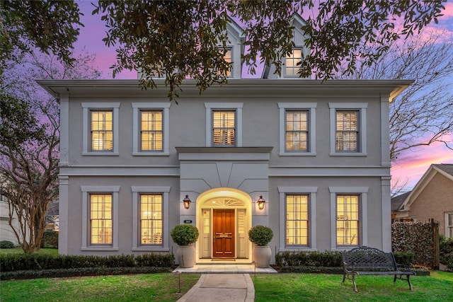 colonial house with a front lawn and stucco siding