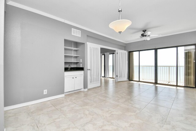 spare room with ornamental molding, sink, ceiling fan, and built in shelves