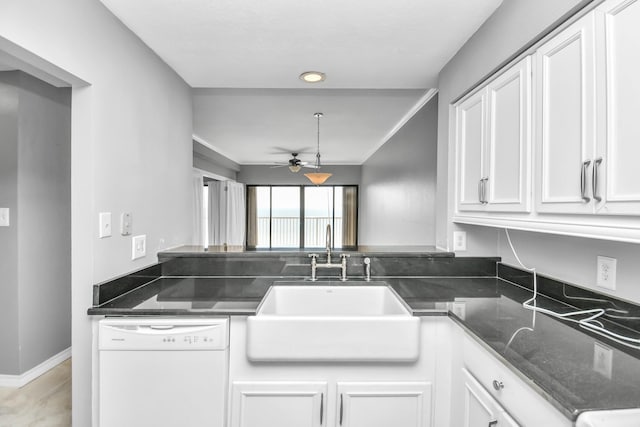 kitchen featuring dark stone countertops, dishwasher, sink, and white cabinets