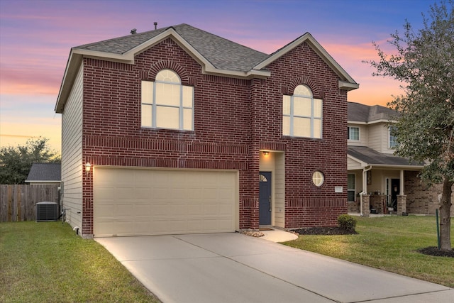 view of front of property featuring a garage, a lawn, and central AC