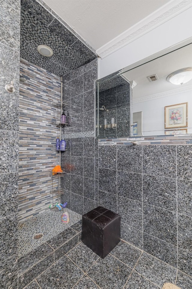 bathroom with ornamental molding and a tile shower