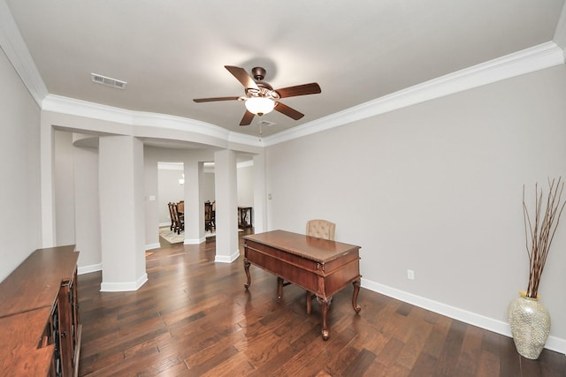 office featuring decorative columns, ornamental molding, dark wood-type flooring, and ceiling fan