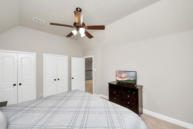 carpeted bedroom with ceiling fan, vaulted ceiling, and two closets