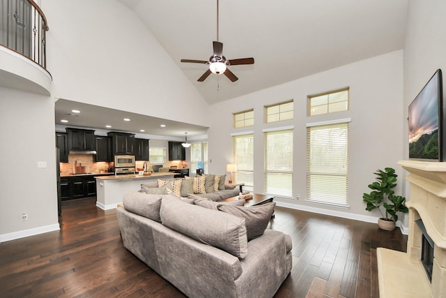 living room featuring ceiling fan, a premium fireplace, dark hardwood / wood-style floors, and high vaulted ceiling