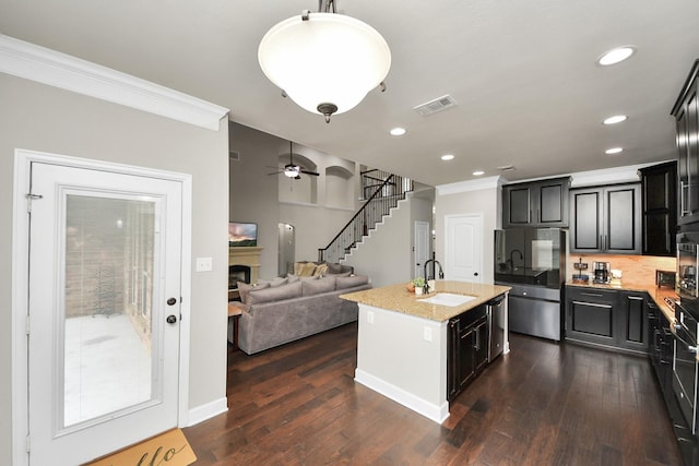 kitchen featuring sink, crown molding, a center island with sink, fridge, and dark hardwood / wood-style flooring