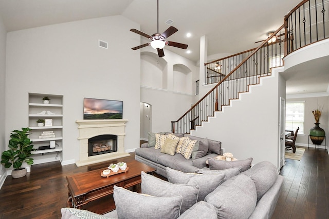 living room featuring dark wood-type flooring, high vaulted ceiling, and built in shelves